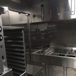 Interior of Pinecrest Summer Camp catering trailer sink and speed racks