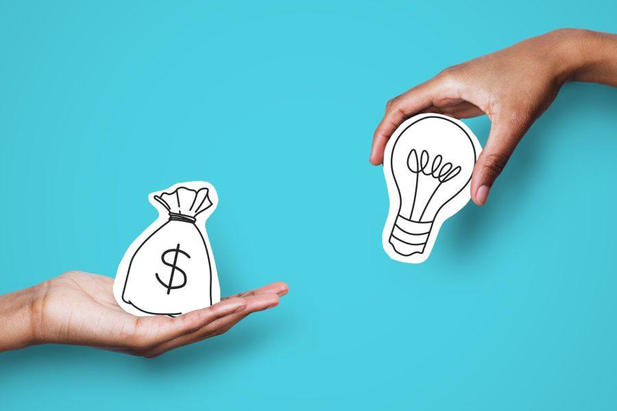 Hands holding bag of money and light bulb on teal background