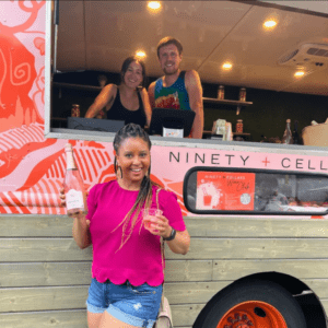 Guest smiling with a bottle of rose wine in front of 90+ Cellars experiential marketing truck