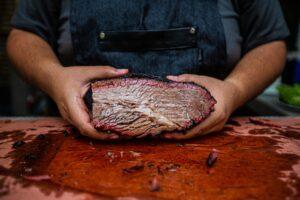 Chef displaying the interior of a perfectly smoked brisket