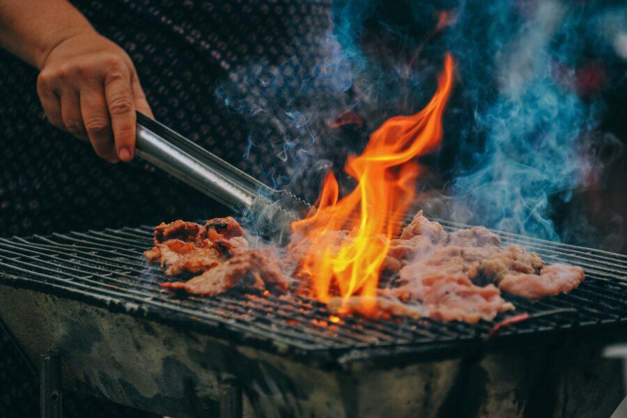 Chef grilling meat over a flame