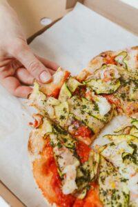 Hand grabbing a slice of veggie pizza