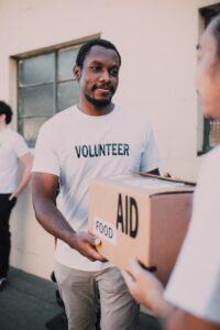 Volunteer worker holding a large cardboard box marked food aid
