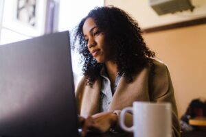 Black woman in business dress working on her laptop