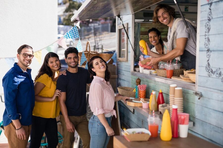 Group of smiling young adult friends buying food from a food truck